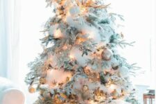 a very snowy Christmas tree with white fluffy garlands, lights, white, silver and gold ornaments, antlers is idea for a winter wonderland space