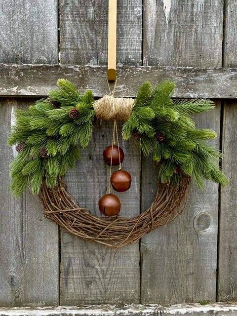 a vine Christmas wreath with evergreens, pinecones, large bells is a very stylish and chic decor idea