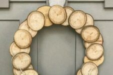 a wood slice Christmas wreath with a burlap bow and some dried herbs for a natural feel