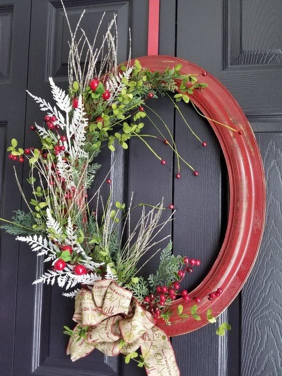 an oval picture frame decorated with faux greenery, silver twigs and branches, berries and a large calligraphy bow for vintage Christmas decor