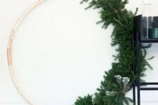 an oversized wreath with evergreens and some berries on one side looks very modern and minimalist