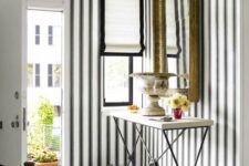 02 an elegant and chic entryway with a black and white floor, black and white stripe wallpaper on the walls, black and white blinds and a vintage frame mirror