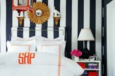 04 an eye-catchy bedroom with a black and white verticla stripe wall, a canopy bed with neutral bedding, a dresser, some lamps and a red pendant lamp