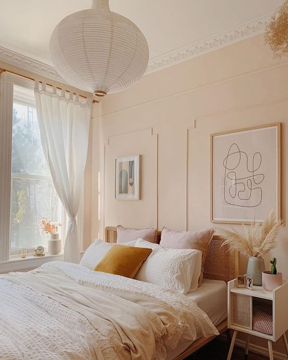 a warm and soothing bedroom with tan walls, a rattan bed with neutral bedding and rattan nightstands and artworks
