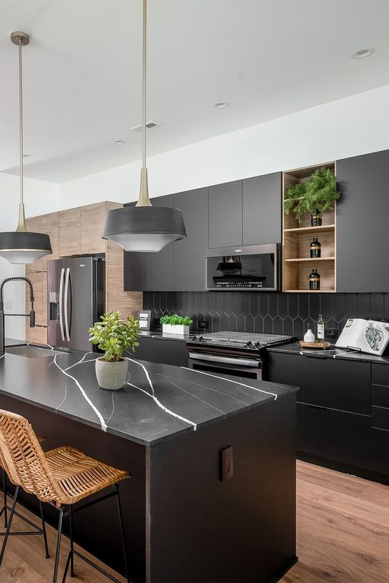 a modern matte black kitchen with a hex tile backsplash, black marble countertops, black pendant lamps and woven chairs