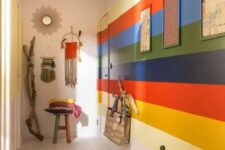 09 a colorful boho entryway with a rainbow accent wall, a bold rug, pendant lamps and hangings plus planters