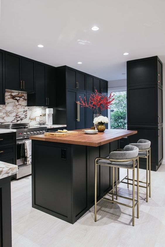 a refined black kitchen with a white marble backsplash, a black kitchen island with a butcherblock countertop plus grey stools