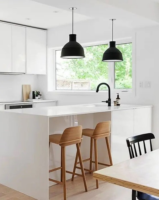 an ultra-modern white space with black lamps and wooden stools looks very laconic and chic