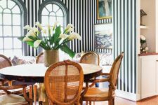 13 a green and white striped dining room with a built-in seating, a round table and woven chairs, a black chandelier