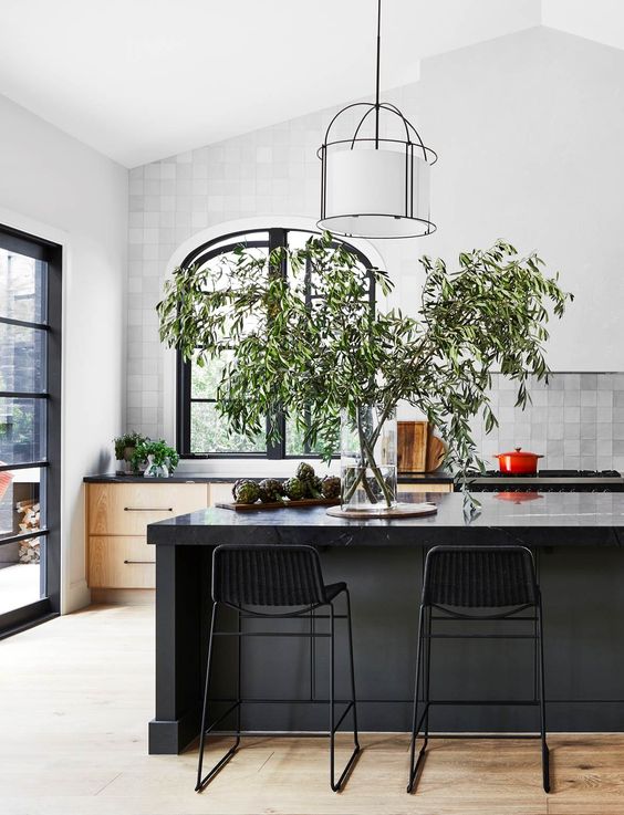 a beautiful kitchen with timber cabinets, a grey tile backsplash, black arched window, a black kitchen island with a marble marble backsplash