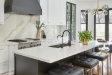 15 a beautiful white kitchen with shaker cabinets, a grey hood, a black kitchen island with a white countertop and black stools