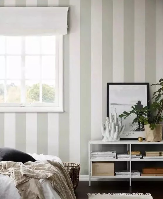 a neutral and ethereal bedroom with a green and white striped wall, neutral textiles and potted plants is very beautiful