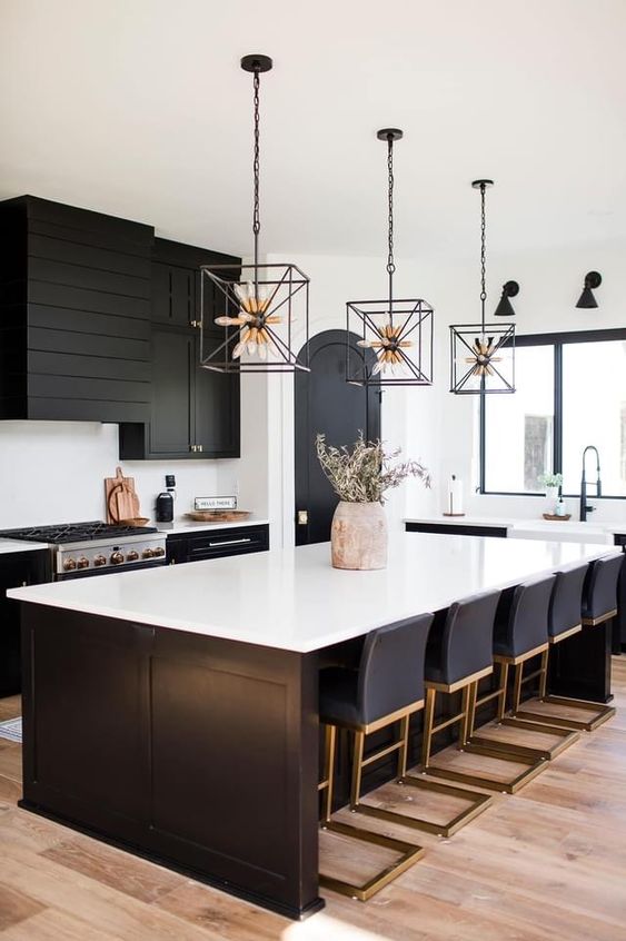 a black farmhouse kitchen with shaker cabinets, a beadboard hood, a large kitchen island with lots of stools