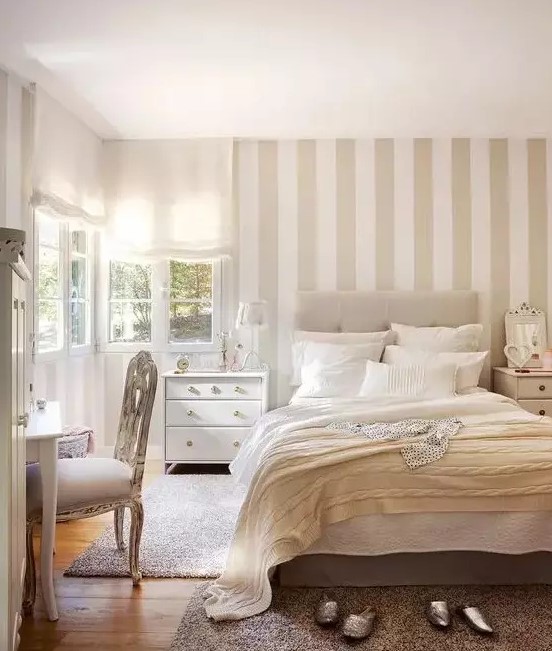 a neutral serene bedroom with a tan and white accent wall, neutral textiles and refined furniture is very welcoming