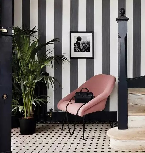 a refined entryway with a striped black and white accent wall and a matching printed monochromatic floor is pure chic
