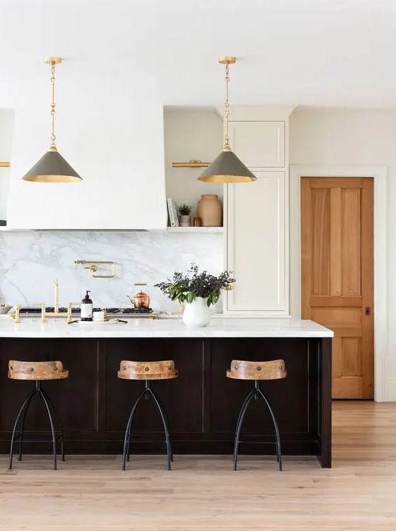 a chic white kitchen with shaker cabinets, open shelves, a large hood, a black kitchen island with a white stone countertop