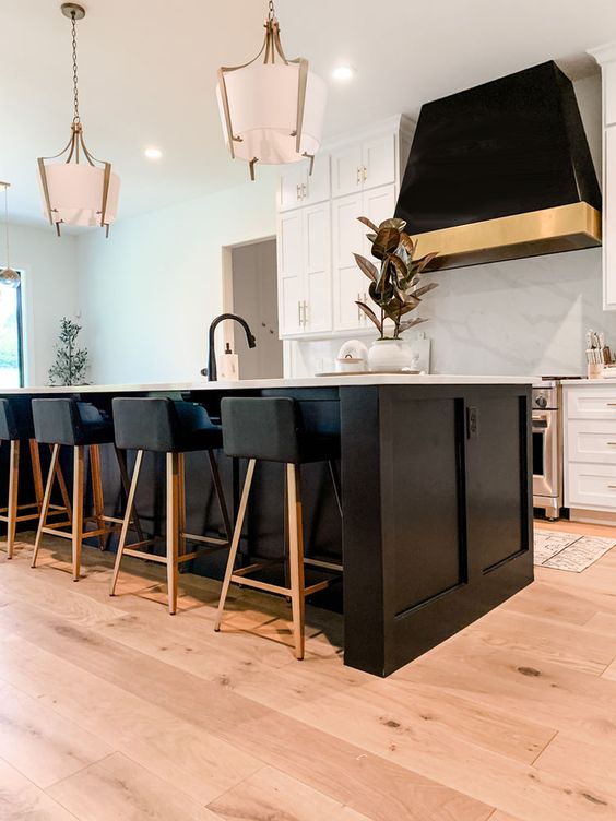 a creative black and white kitchen with shaker cabinets, a large kitchen island, a statement black hood and stools