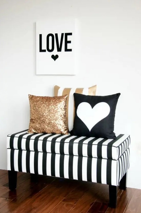 a black and white striped storage bench with black and gold sequin pillows is a glam piece for an entryway or a living room