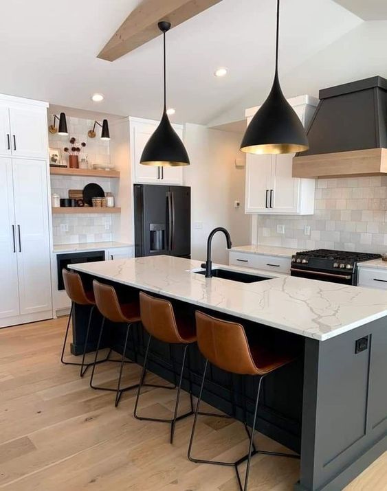 a modern black and white kitchen with white shaker cabinets, a black kitchen island, white countertops and a backsplash, black lamps
