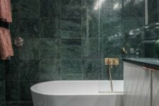 29 green marble tiles covering the whole bathroom make it a refined and a bit moody space