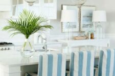 30 a neutral coastal kitchen with white cabinets, glass and usual ones, a console table with decor, a kitchen island and tall blue and white stools