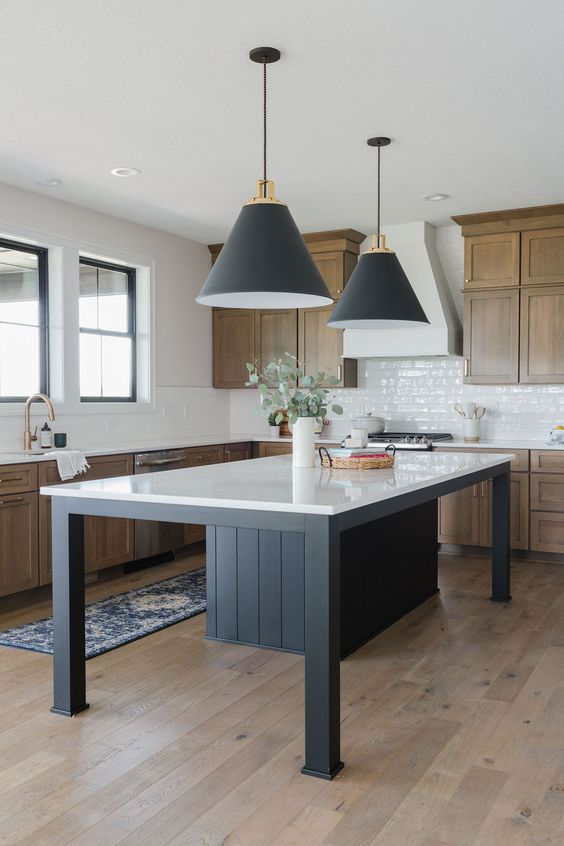 a modern rustic kitchen with timber cabinets, a white tile backsplash, a black kitchen island with a white countertop