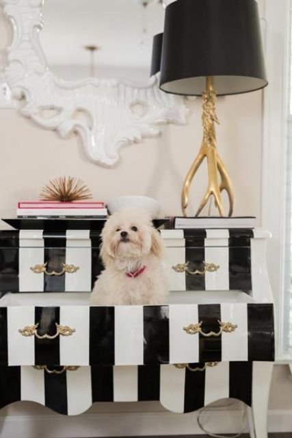 a quirky black and white sideboard with gold handles, a black lamp on a branch stand are a glam combo for a refined home