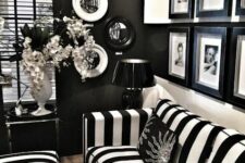 33 a refined vintage-inspired black and white living room with black walls, a black and white strip sofa and poufs, a black and white gallery wall and some decorative plates