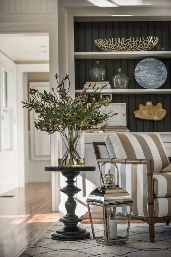 a stylish and welcoming space with built in shelves and a cabinet, a striped bamboo chair and a side table plus a lantern