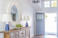 38 a seaside entryway with a shabby chic wooden console table, blue lamps and a round mirror in a whitewashed frame, a striped rug