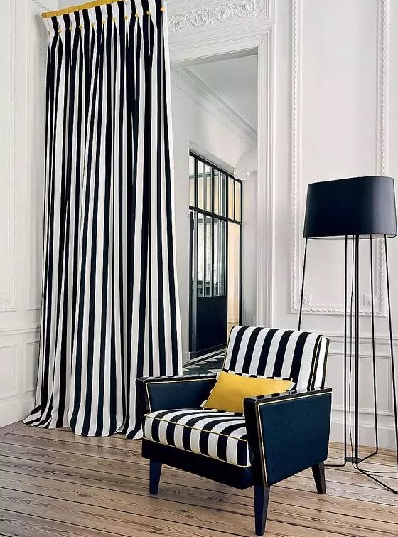 bold and refined interior with paneling and stucco, a striped chair and a matching curtain plus a black floor lamp
