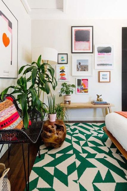 a mid century modern space with a bed, a rattan chair, a stained bench and a gallery wall plus a bold geometric rug