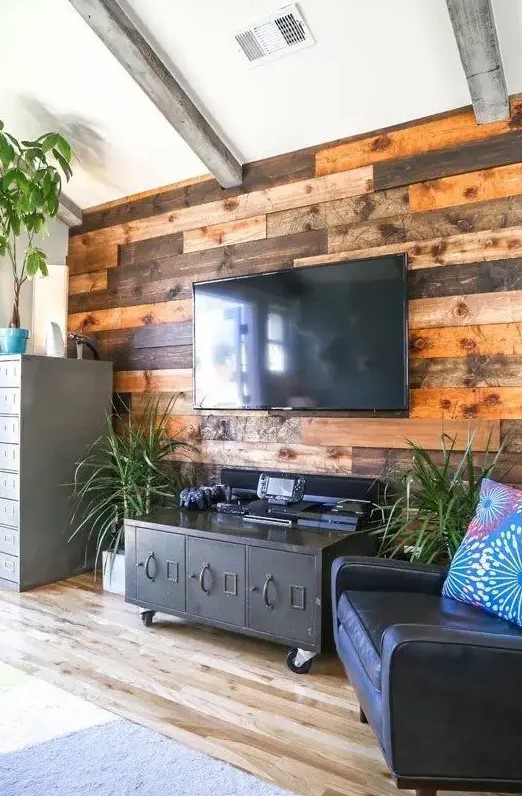 a weathered and stained wood accent wall softens the industrial-inspired living room with vintage touches