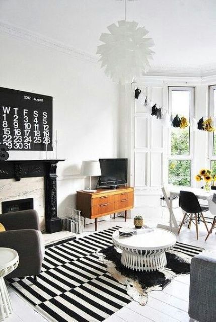 a Scandinavian living room with a faux fireplace, a striped rug, black and white furniture and some mid-century modern items
