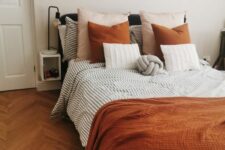 52 a welcoming bedroom with a black bed, rust and striped grey bedding, a printed rug and a mini gallery wall