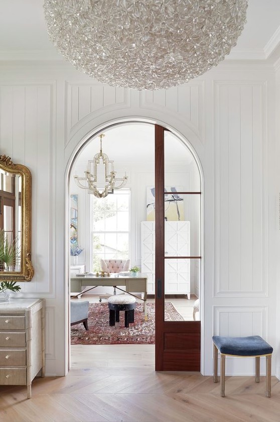 a refined vintage-inspired house with a double-height arched doorway and a rich-stained arched glass pocket door