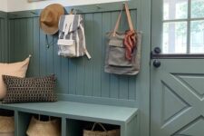 a beautiful farmhouse mudroom with beadboard on the walls, a matching bench and a door, some baskets and pillows