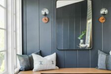 a boho mudroom with midnight blue beadboard, a corner bench, baskets and pillows plus a mirror and wall sconces