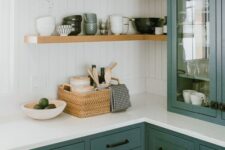 a bright green kitchen with shaker cabinets, open corner shelves, white stone countertops and a beadboard backsplash