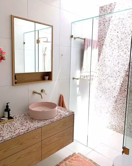 a chic contemporary bathroom with a pink terrazzo wall in the shower, a floating vanity with a pink terrazzo countertop plus a pink sink