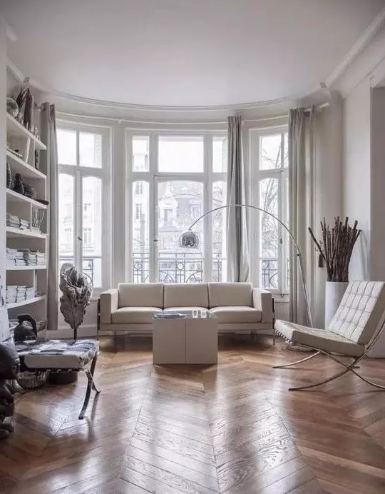 a contemporary Parisian living room with all-whites and a hardwood parquet floor to soften the space