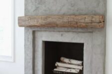 a contemporary concrete fireplace with a rough wood mantel and firewood in the fireplace – the mantel cozies the fireplace up