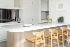 a contemporary white kitchen with a black mirror backsplash, a curved and ribbed kitchen island and tall stained stools