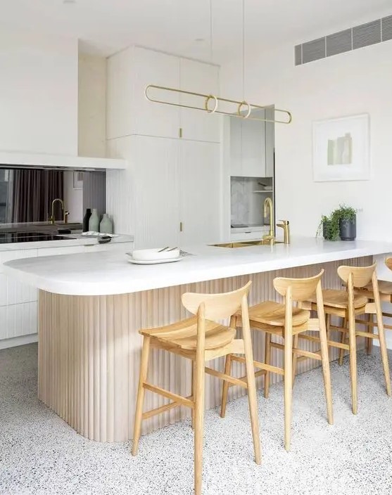 a contemporary white kitchen with a black mirror backsplash, a curved and ribbed kitchen island and tall stained stools