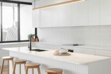 a contemporary white kitchen with sleek cabinets, a skinny tile backsplash and matching kitchen island decor, with stained stools