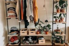 a cool and simple makeshift closet of a metal and wood clothes rack with open shelves, crates and railing for hanging clothes