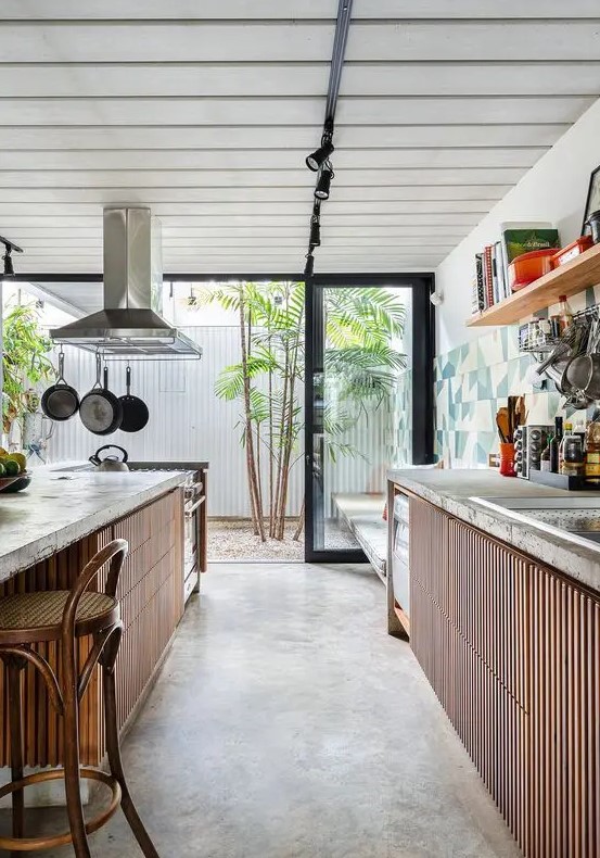 a cool indoor outdoor kitchen with ribbed cabinets, concrete countertops, a large matching kitchen island with an eating zone