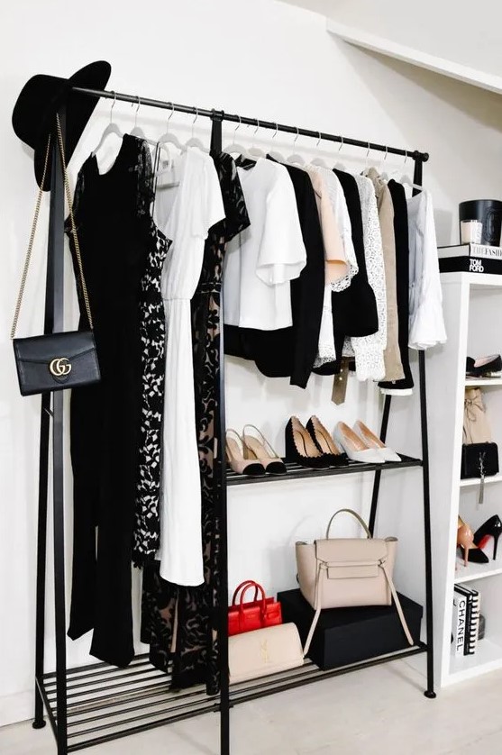 a cool makeshift closet with a black clothes rack that includes space for shoes and a tall storage unit with open shelves