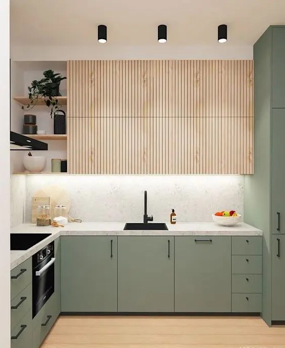 a cool modern kitchen with plain green cabinets and fluted stained upper ones, a white stone countertop and a backsplash, black fixtures