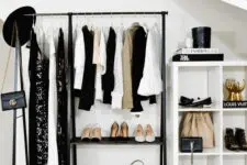 a cool modern makeshift closet with a black clothes rack, a white storage unit and lots of cool clothes and shoes on display